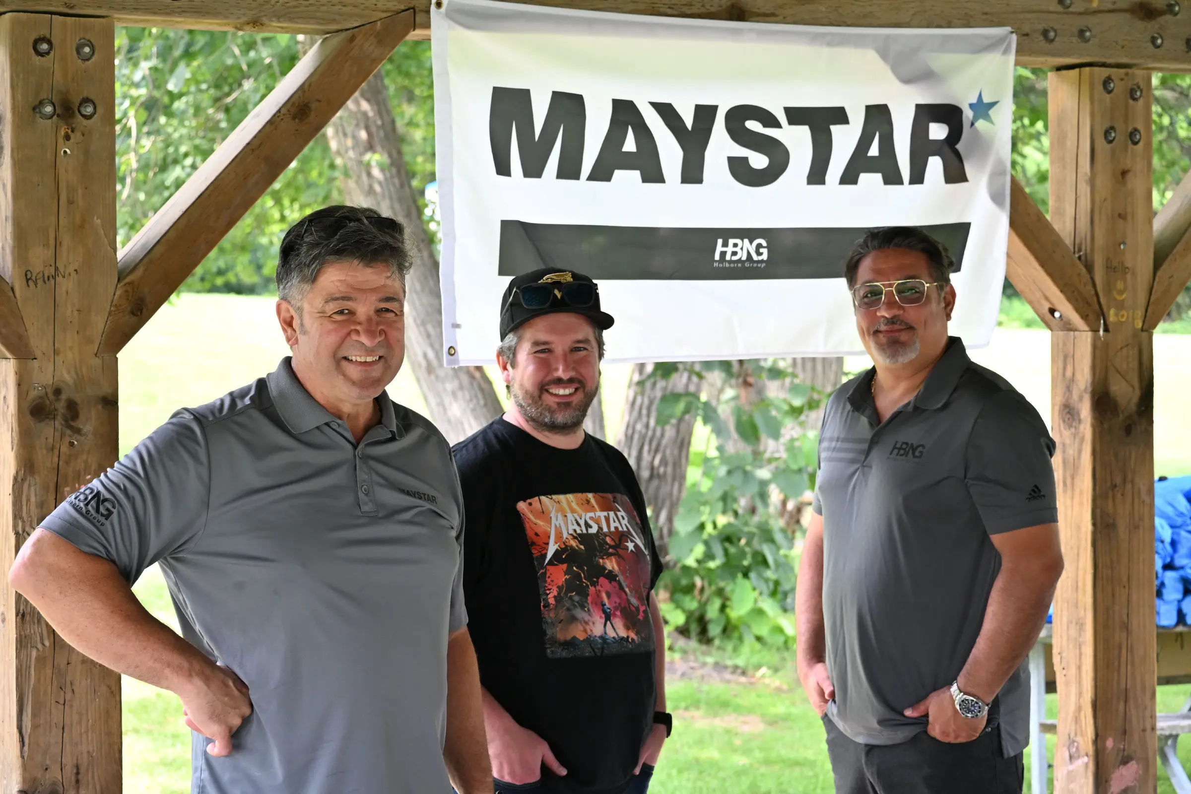 Maystar team members smiling in front of the company sign.