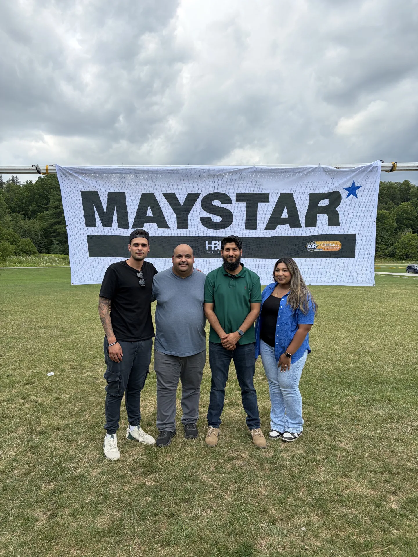 Maystar team members posing in front of the company sign.
